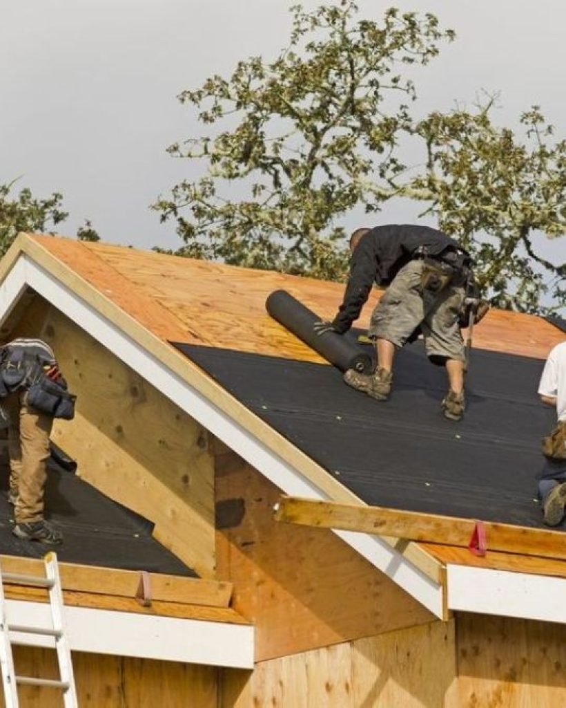 Workers applying roofing material on a Seattle home, highlighting expert roofing services in the area.